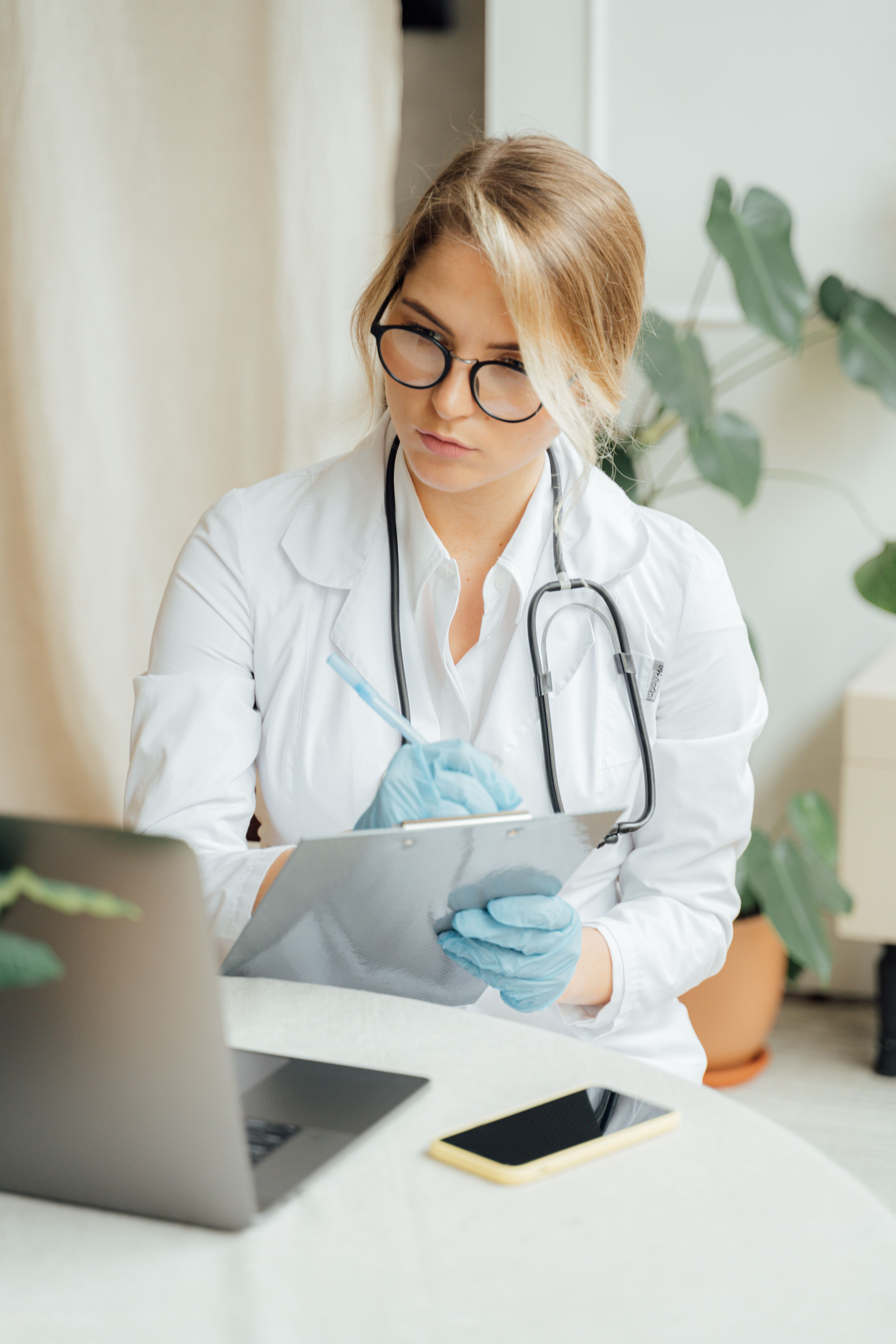 Doctor reviewing patient notes on a clipboard at her desk